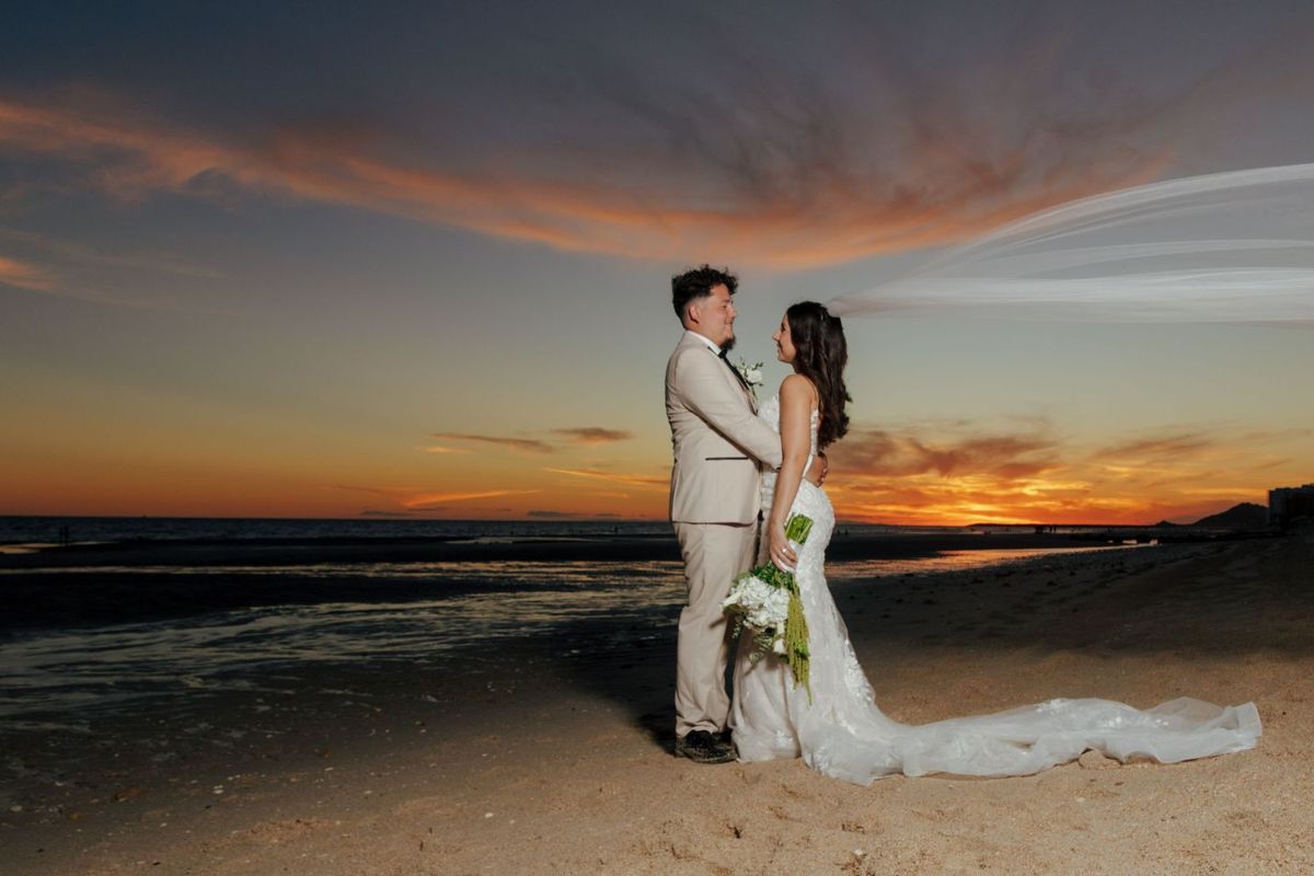 Newly married couple on a Puerto Peñasco beach beneath a sunset sky
