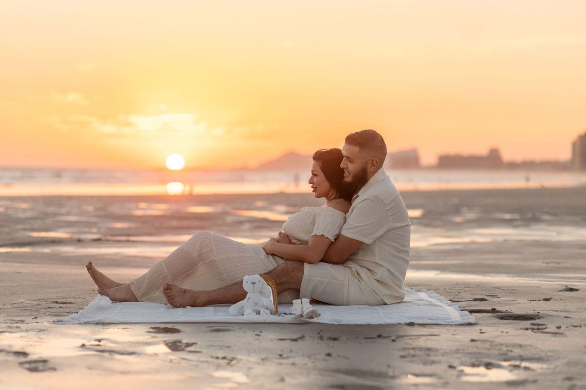 Expectant couple sharing a quiet maternity portrait on the beach at sunset